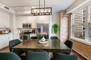 Una cocina moderna con armarios blancos, electrodomésticos de acero inoxidable y una mesa de comedor de madera oscura con sillas.