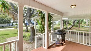 A covered porch with a grill and propane tank, surrounded by trees and a view of a residential street. - 2 Mi to Mashes Sands Beach: Quiet Home w/ Dock! (Panacea)