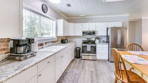 A modern kitchen with white cabinets, a stainless steel refrigerator, a microwave, and a coffee maker. - 2 Mi to Mashes Sands Beach: Quiet Home w/ Dock! (Panacea)