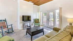 A living room with a wooden ceiling, a television, a green armchair, a sofa, and a coffee table. - 2 Mi to Mashes Sands Beach: Quiet Home w/ Dock! (Panacea)