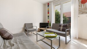 A modern living room with a grey sofa, two armchairs, a coffee table, and a TV on a wooden stand. - Ô Soleil - Avec piscine privée (Vendres)