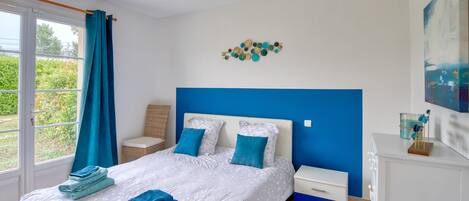 Une chambre à coucher avec un lit, des tables de chevet, une commode et une fenêtre avec des rideaux.