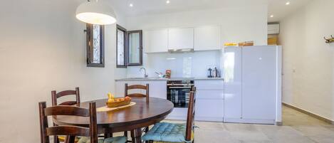 A modern kitchen with white cabinets, a built-in oven, and a white refrigerator.
