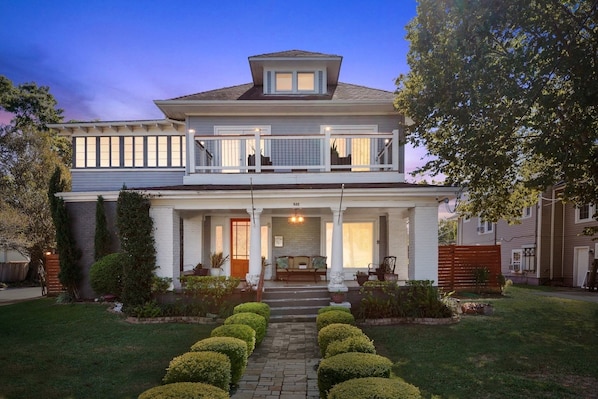 A two-story house with a front porch, a covered balcony, and a well-maintained garden.