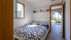 Un dormitori amb un llit, una finestra, una porta i vistes a l'exterior.