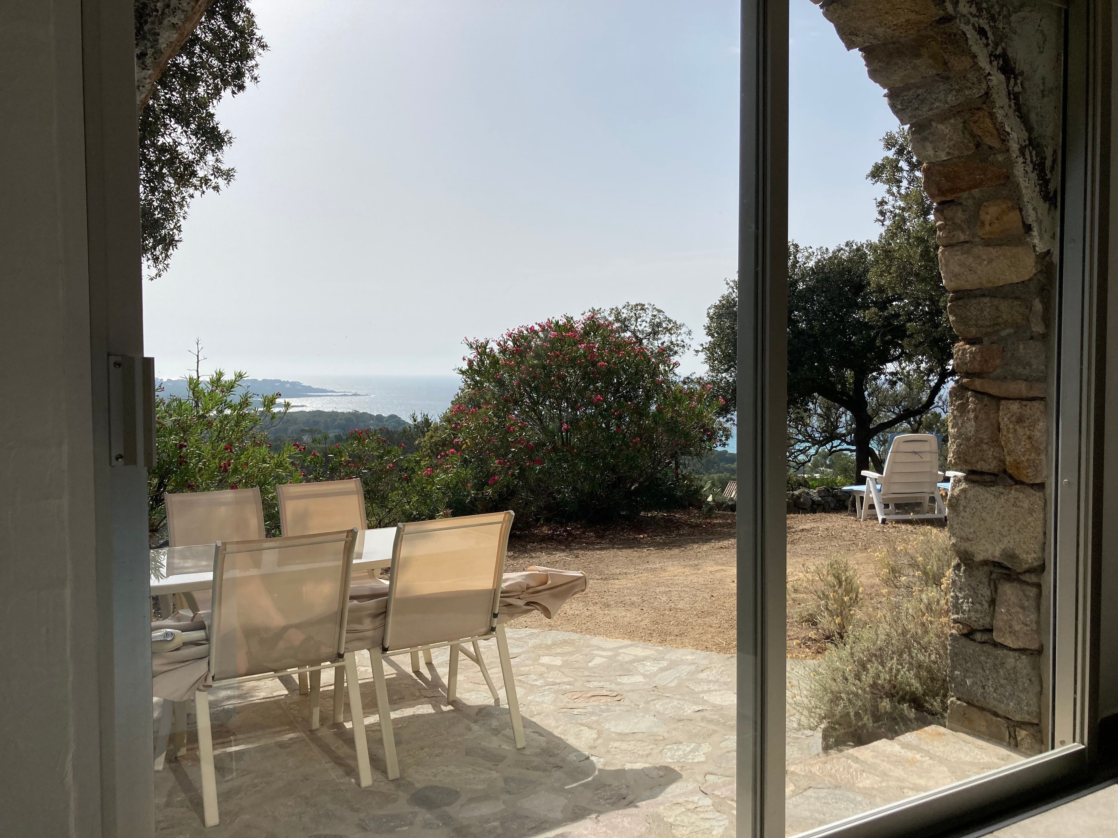 Eine Terrasse im Freien mit Tisch und Stühlen, einer Steinmauer und Blick auf die Landschaft.