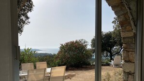 Un pati exterior amb taula i cadires, una paret de pedra i una vista del paisatge.