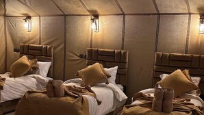 A luxury camp with three beds, each with a headboard and pillows, and a warm, cozy ambiance. - Asafar Luxury Camp (Rissani)