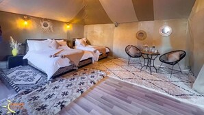 A tent-style bedroom with two beds, a dining table, and chairs. - Asafar Luxury Camp (Rissani)
