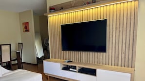 Ein modernes Wohnzimmer mit einem an einer Holzwand montierten Flachbildfernseher, einem weißen Sofa und einer Holzunterhaltungseinrichtung mit Schubladen.