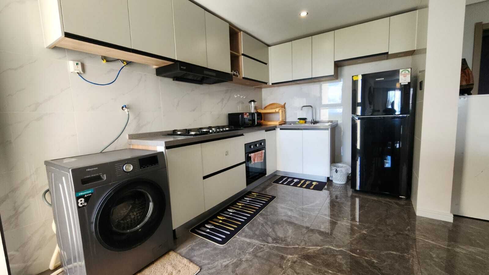 A modern kitchen with a built-in washer, a stove, and a refrigerator.