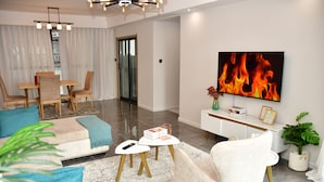 Un salon moderne avec un canapé, des fauteuils, une table basse et un téléviseur fixé au mur.