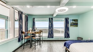 A room with a bed, a table with chairs, a window with curtains, and a painting on the wall.
