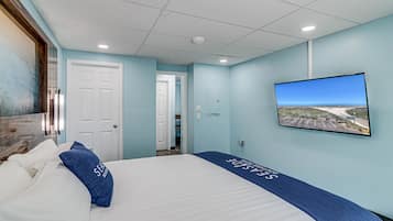 A hotel room with a bed, a television mounted on the wall, and a door leading to another room.