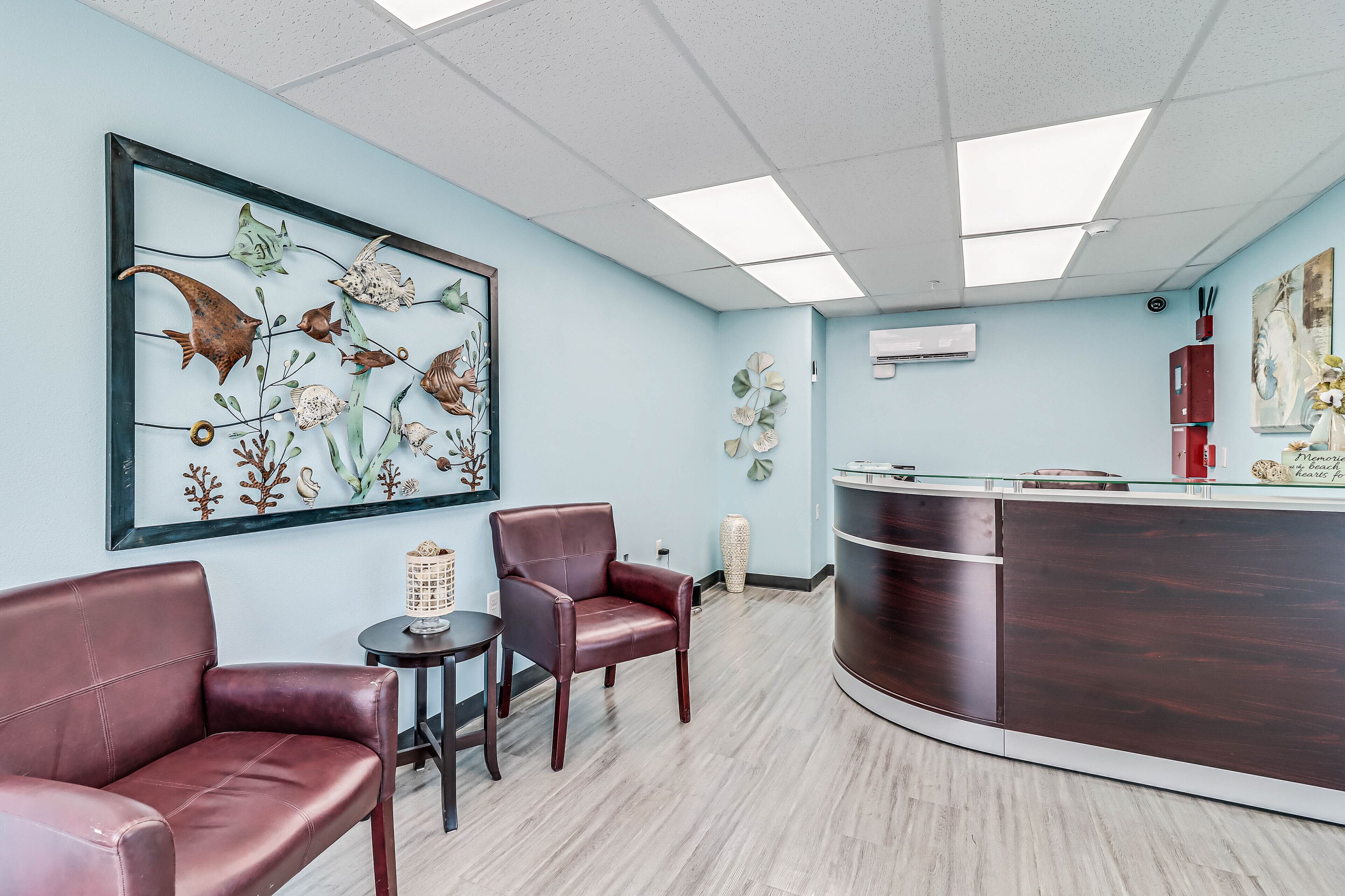 A reception area with a large wall mural of marine life, leather seating, a reception desk, and a small side table.