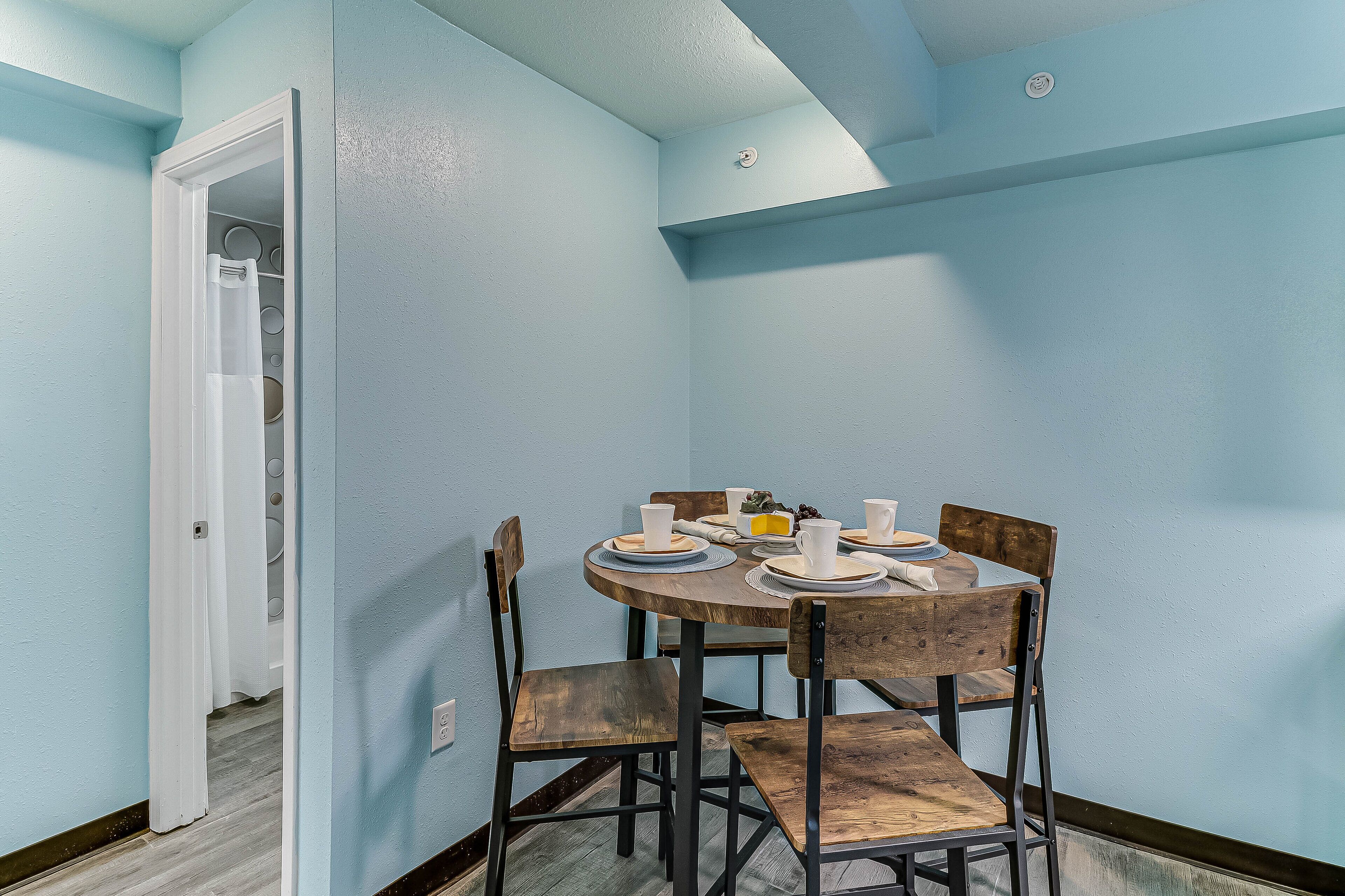 A dining area with a round table set for four, wooden chairs, and a white door leading to a closet.