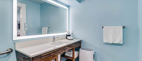 A bathroom with a double sink, wooden vanity, a large mirror, a towel rack, and a hand dryer.
