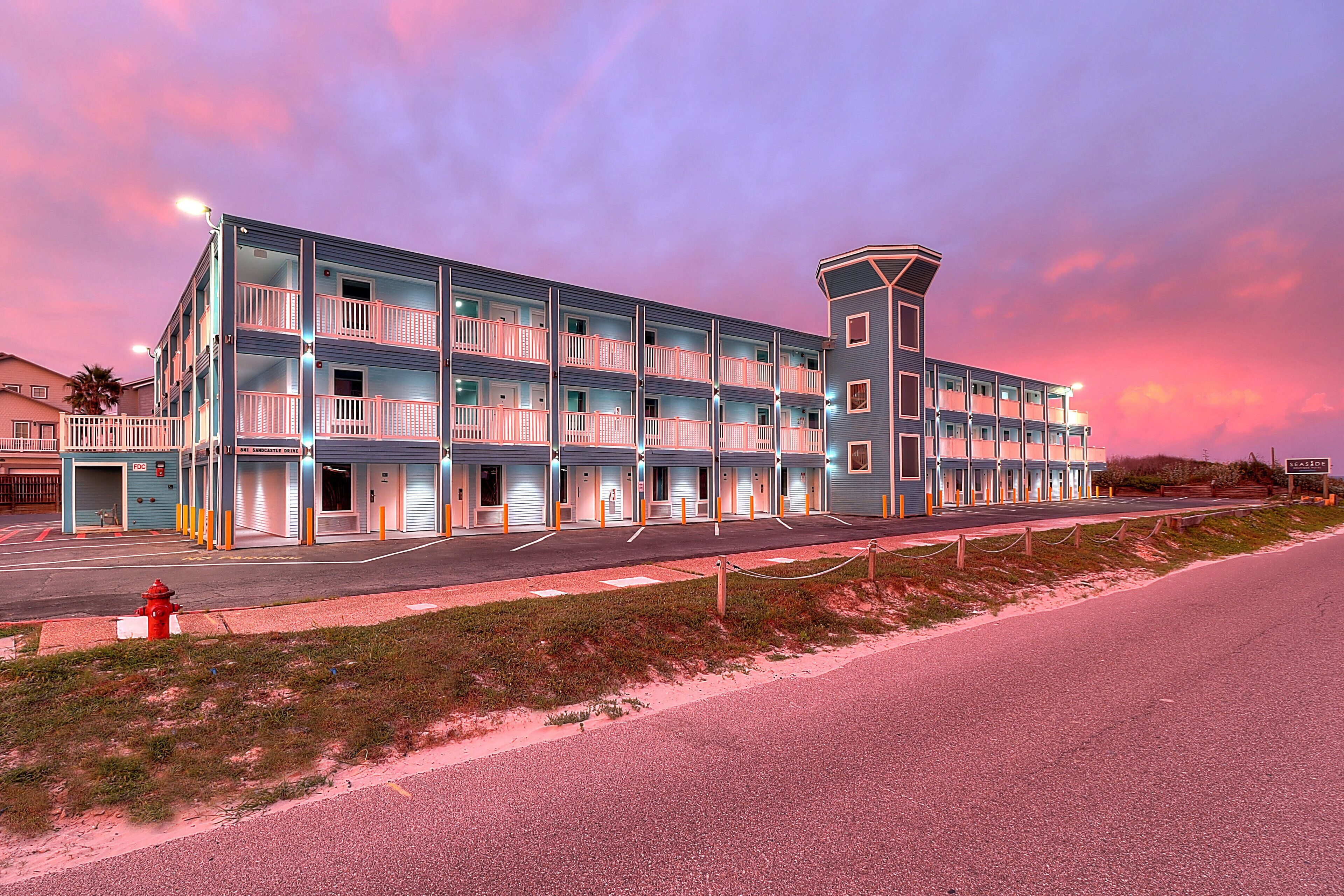 Un hotel a più piani con balconi, una torre centrale e posizione fronte spiaggia.