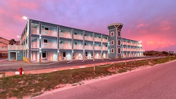 Un hotel a più piani con balconi, una torre centrale e posizione fronte spiaggia.