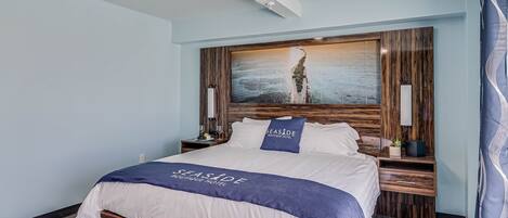 A hotel room with a large bed, wooden headboard, and a painting of a person on a beach.