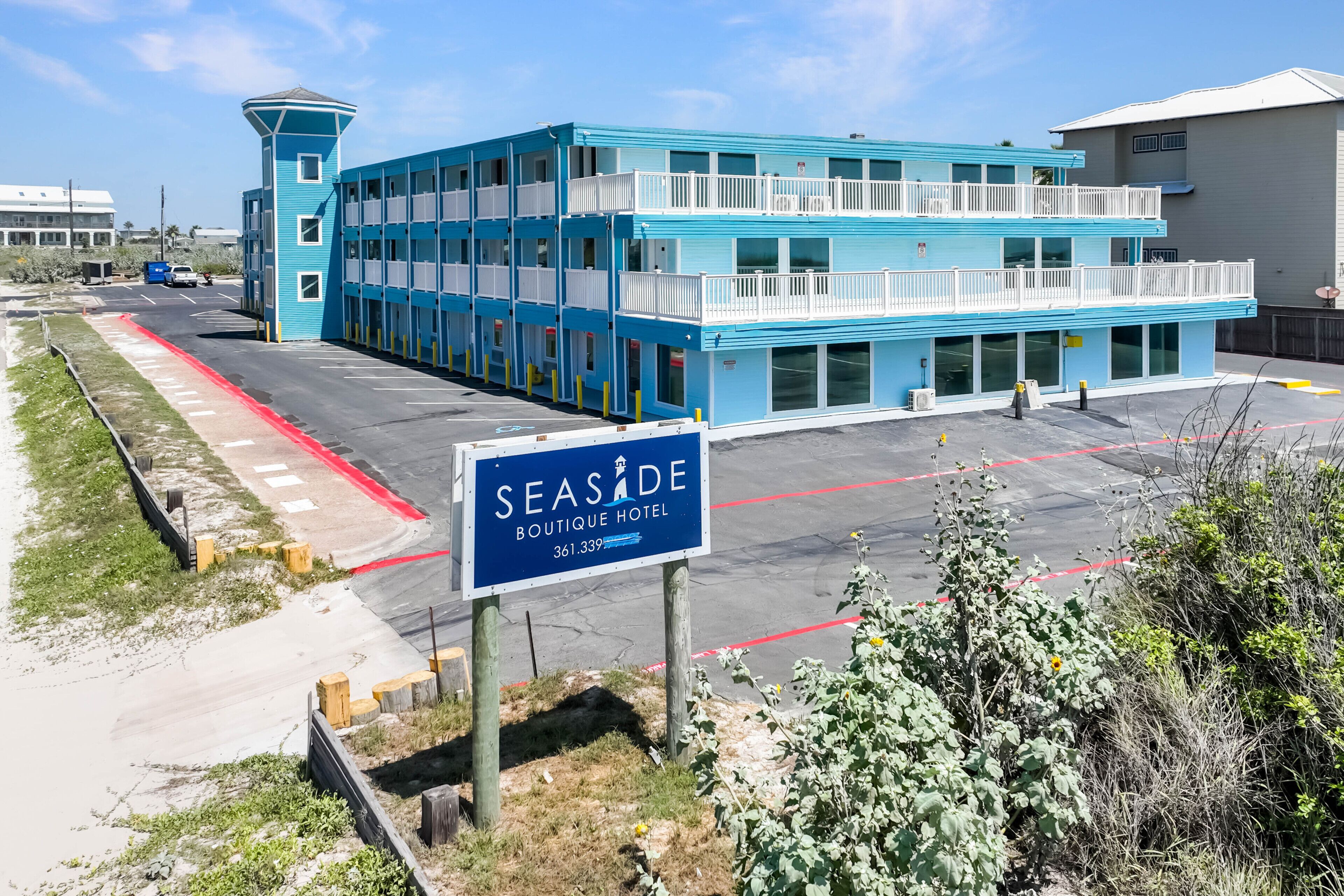 A blue and white multi-story building with a sign reading "SEASIDE BOUTIQUE HOTEL 361.339".