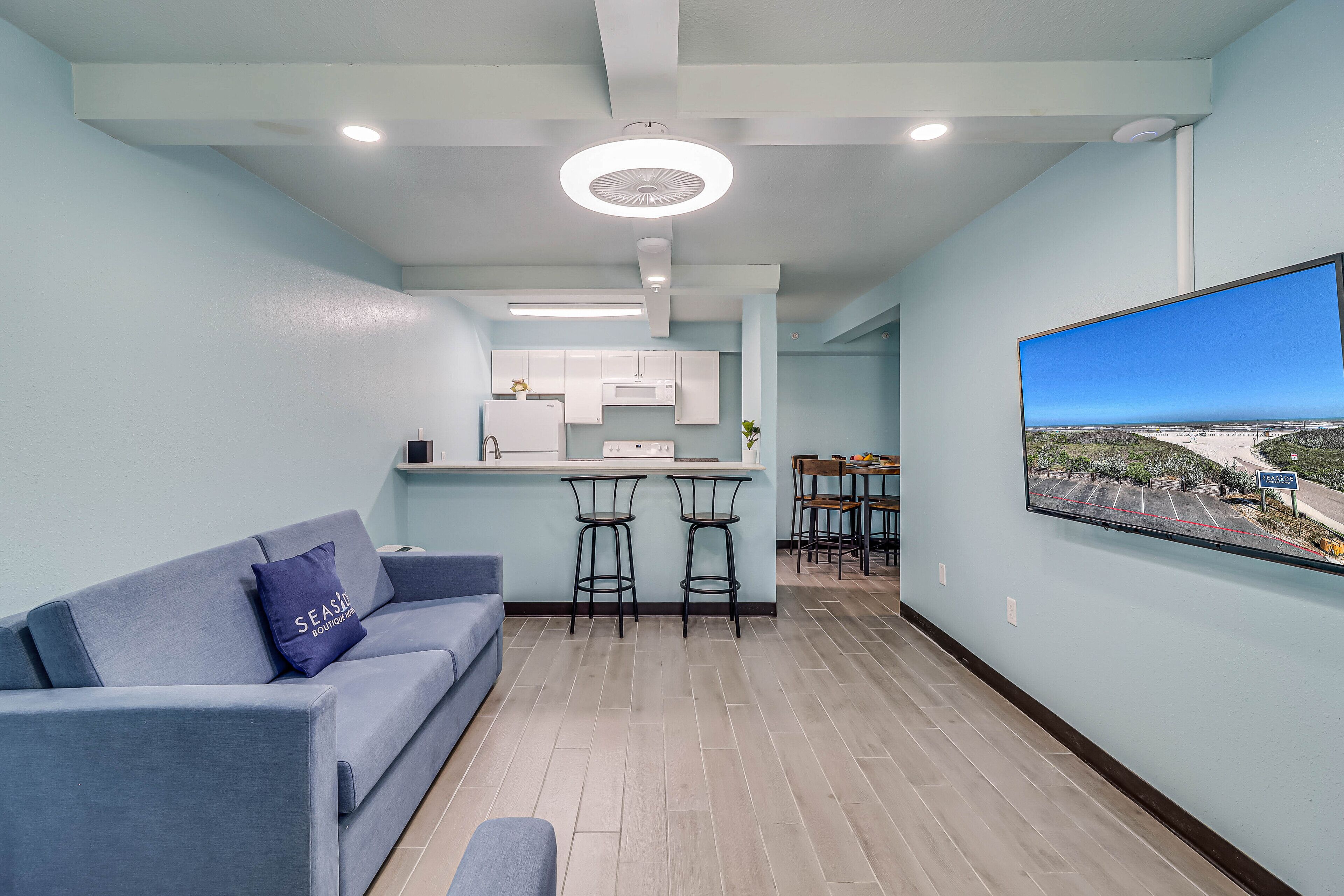 A modern living room with a sofa, a coffee table, and a TV mounted on the wall.