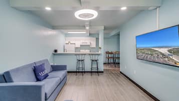 Un salon moderne avec un canapé, une table basse et un téléviseur fixé au mur.