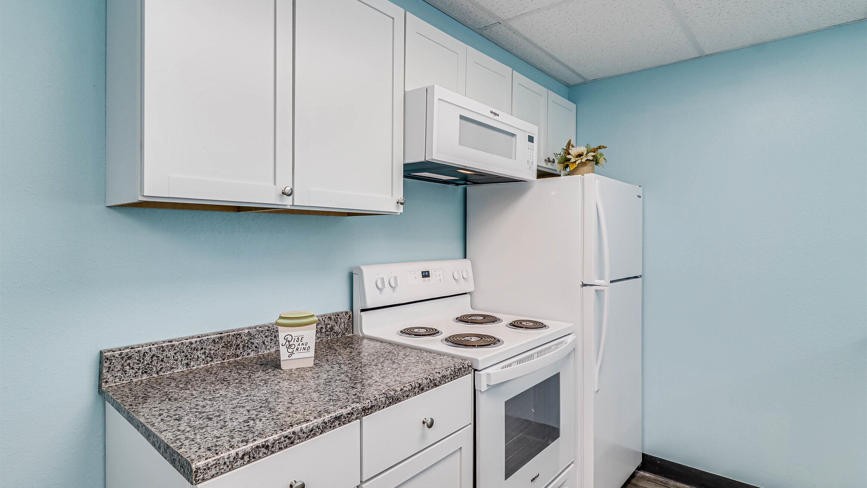 A kitchen with white cabinets, a microwave, a stove, and a refrigerator.