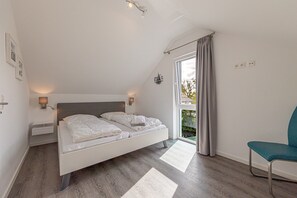 Ein Schlafzimmer mit einem Bett, einem Sessel, einem Fenster und einer Tür.
