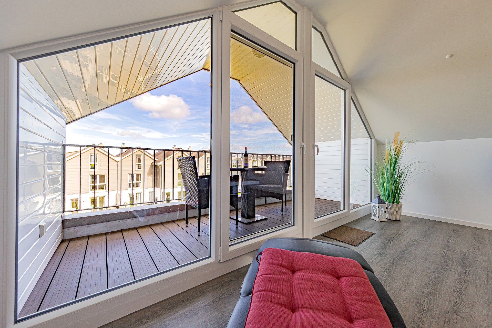 Ein Balkon mit Blick auf Nachbarhäuser, ein Tisch mit Stühlen und ein Blumentopf.