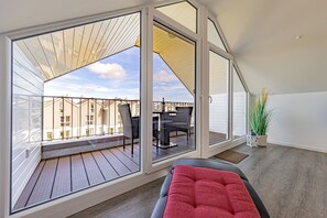 Un balcón con vistas a casas vecinas, una mesa con sillas y una planta en maceta.