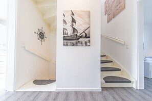 Eine Treppe mit Wanddekoration als Kompass, einer gerahmten maritimen Illustration und einem modernen Design.
