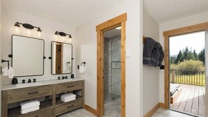 A bathroom with two sinks, wooden vanity, marble flooring, and a glass shower enclosure. - Lone Moose Lookout | Big Sky Meadow (Big Sky)