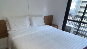 A hotel room with a large bed, a nightstand, and a window with a view of buildings. - Tela de Cinema! Novinho Prox. Paulista c/ Vaga (Consolação São Paulo)