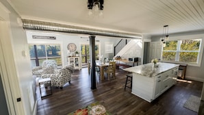 A spacious living area with a large island, wooden flooring, and a view of the outdoors.