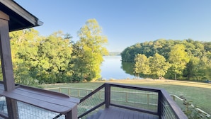 A wooden deck with a view of a lake surrounded by trees.