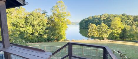 A wooden deck with a view of a lake surrounded by trees.