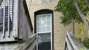 Un escalier en bois menant à un bâtiment doté d’une fenêtre.