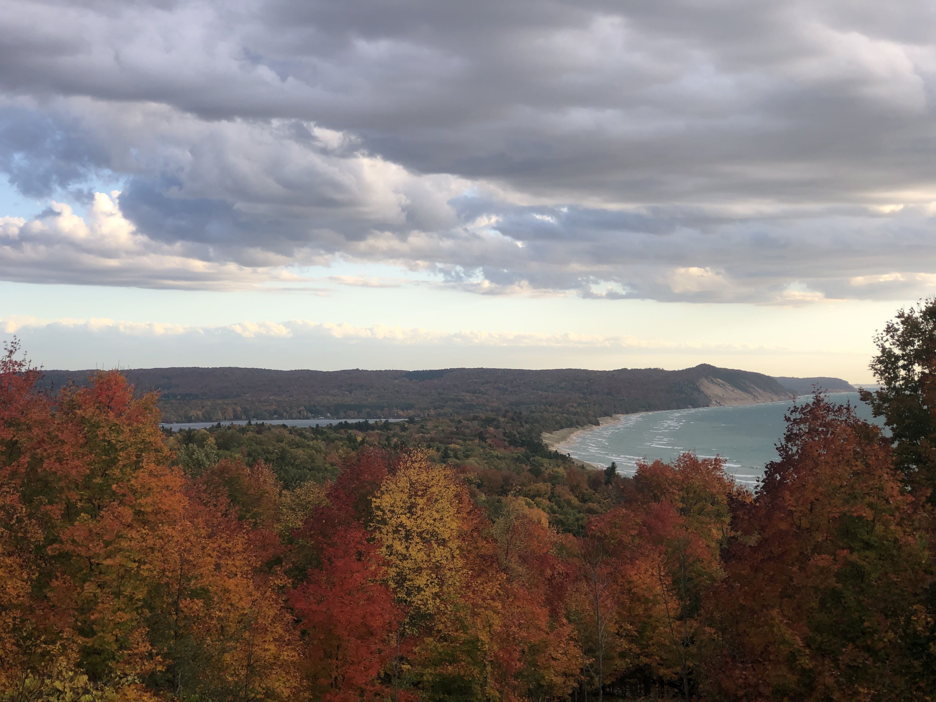 Een kustlandschap met herfstkleuren, een strand en een heuvelachtig achtergrondlandschap.