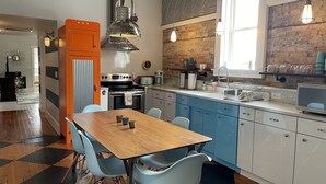 Une cuisine moderne avec une table à manger en bois, des chaises bleues et un mur en briques.