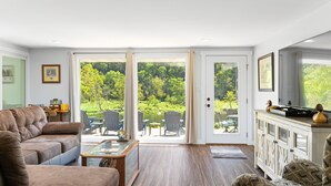 A living room with a sofa, a coffee table, and a view of a garden through glass doors. - NEW LISTING- Riverfront / Unique / Perfect location/ Private  (Lakeview)