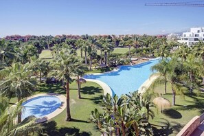 Un complexe hôtelier doté d’une grande piscine, entourée de palmiers et de verdure.