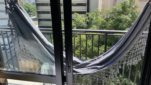 Un'amaca fissata tra i balconi, con vista su edifici e alberi.