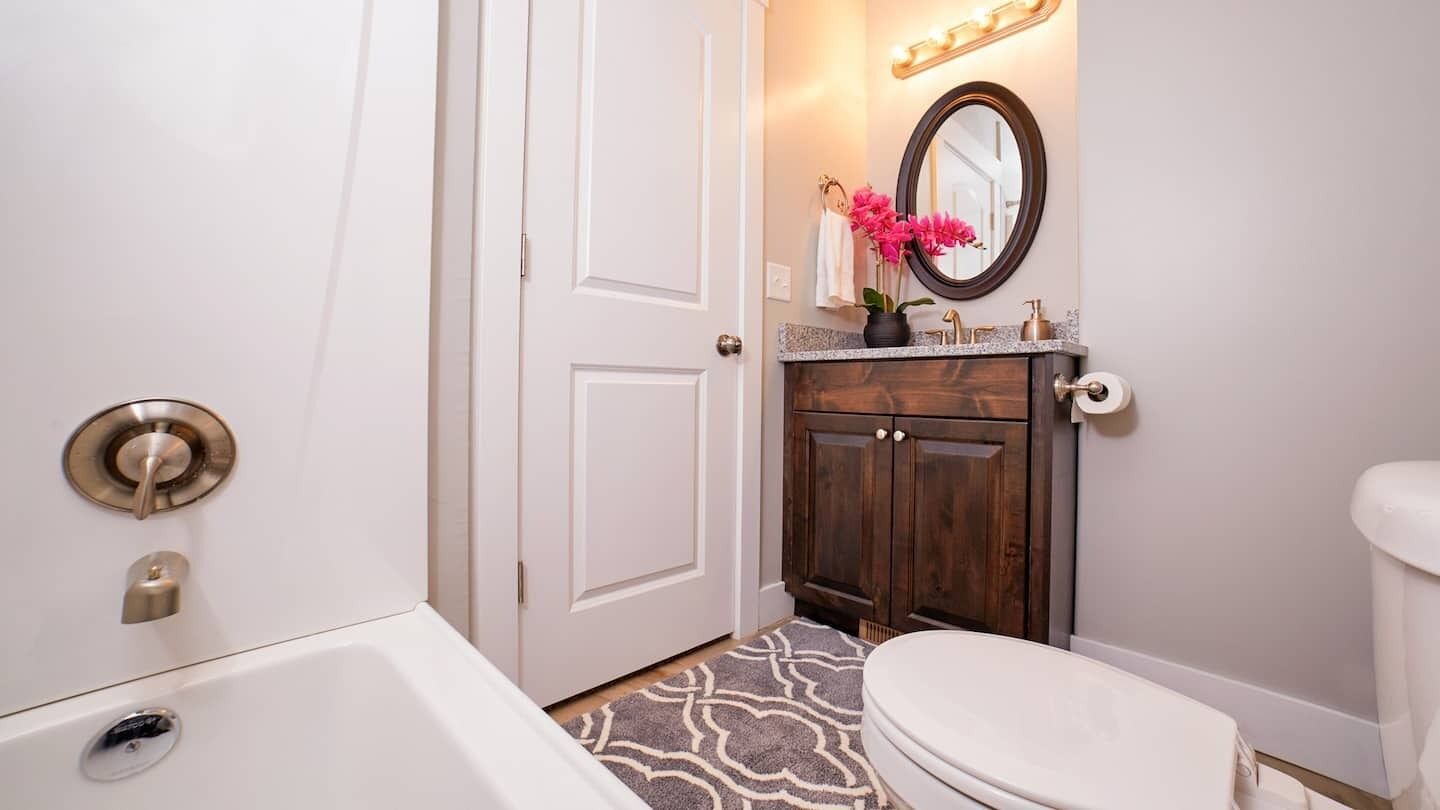Une salle de bain avec une baignoire blanche, des toilettes et un meuble-lavabo doté d’un miroir et d’un évier.