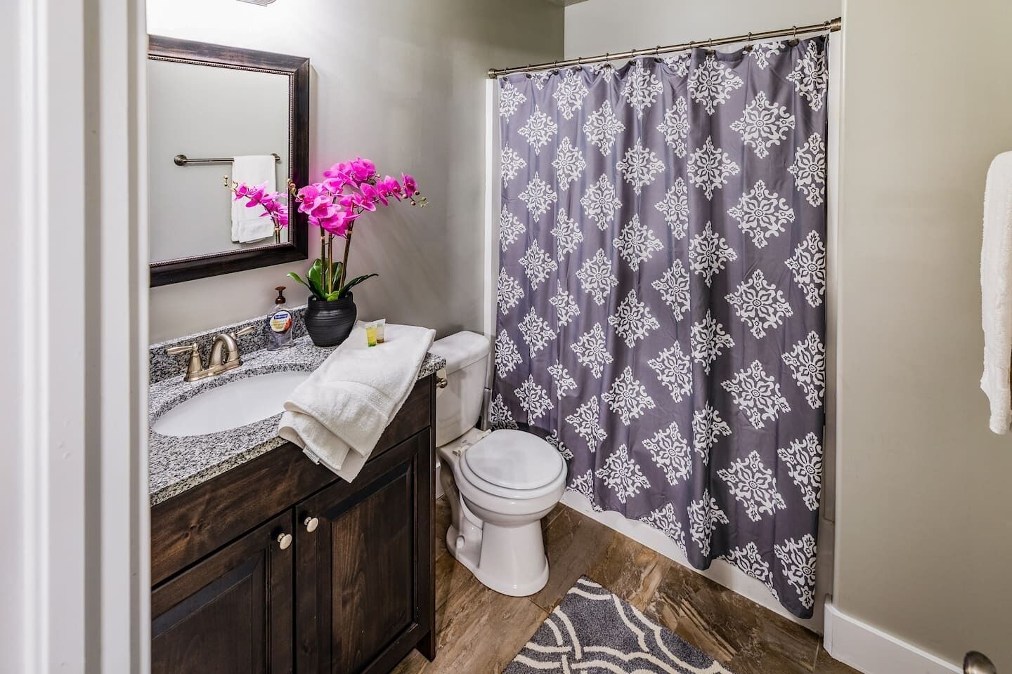 A bathroom with a vanity, sink, mirror, and toilet.