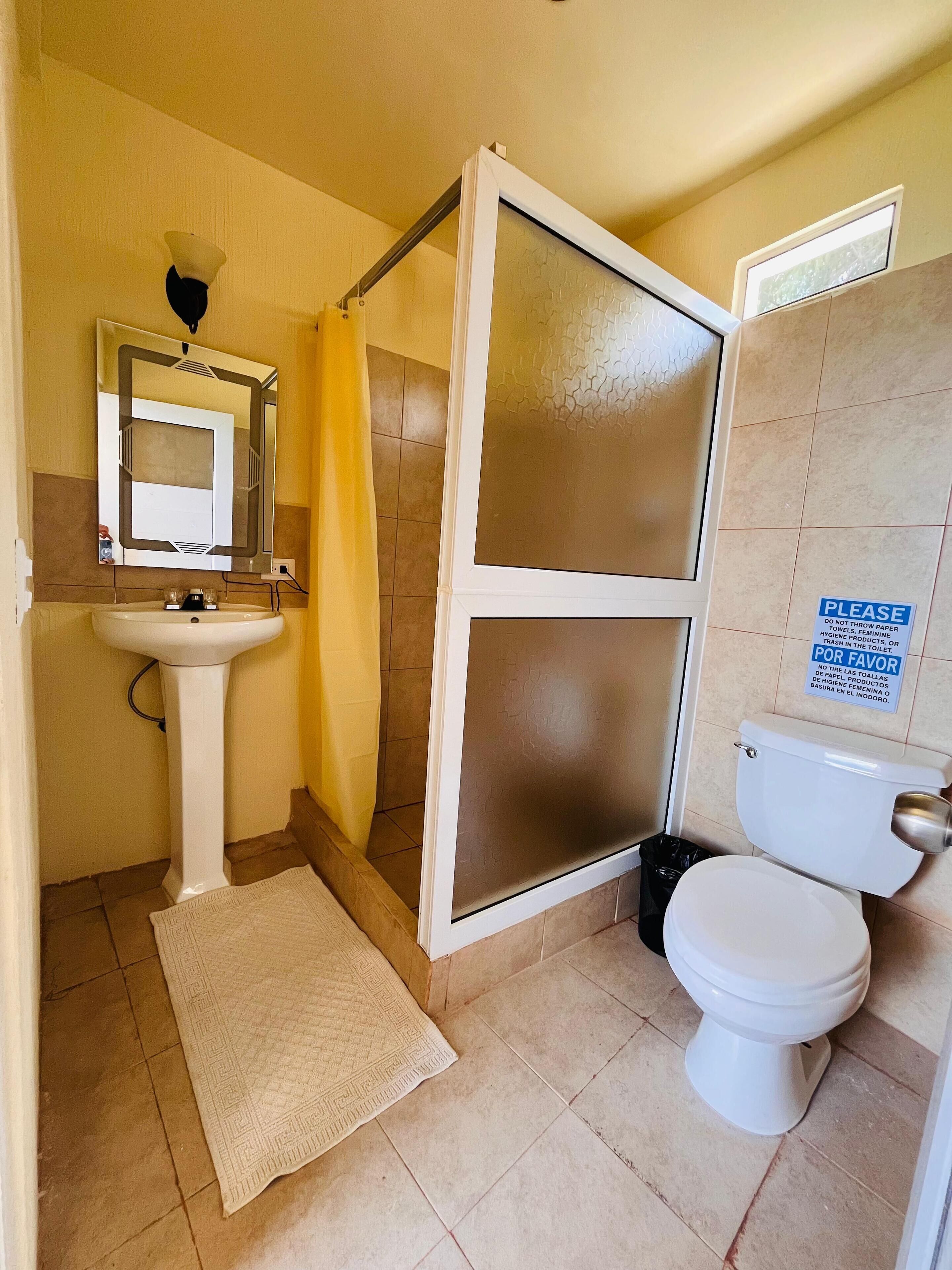 A bathroom with a toilet, sink, and shower.