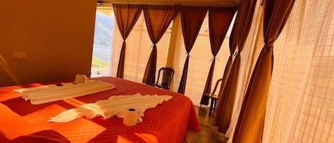 A hotel room with a large bed, a chair, and curtains.
