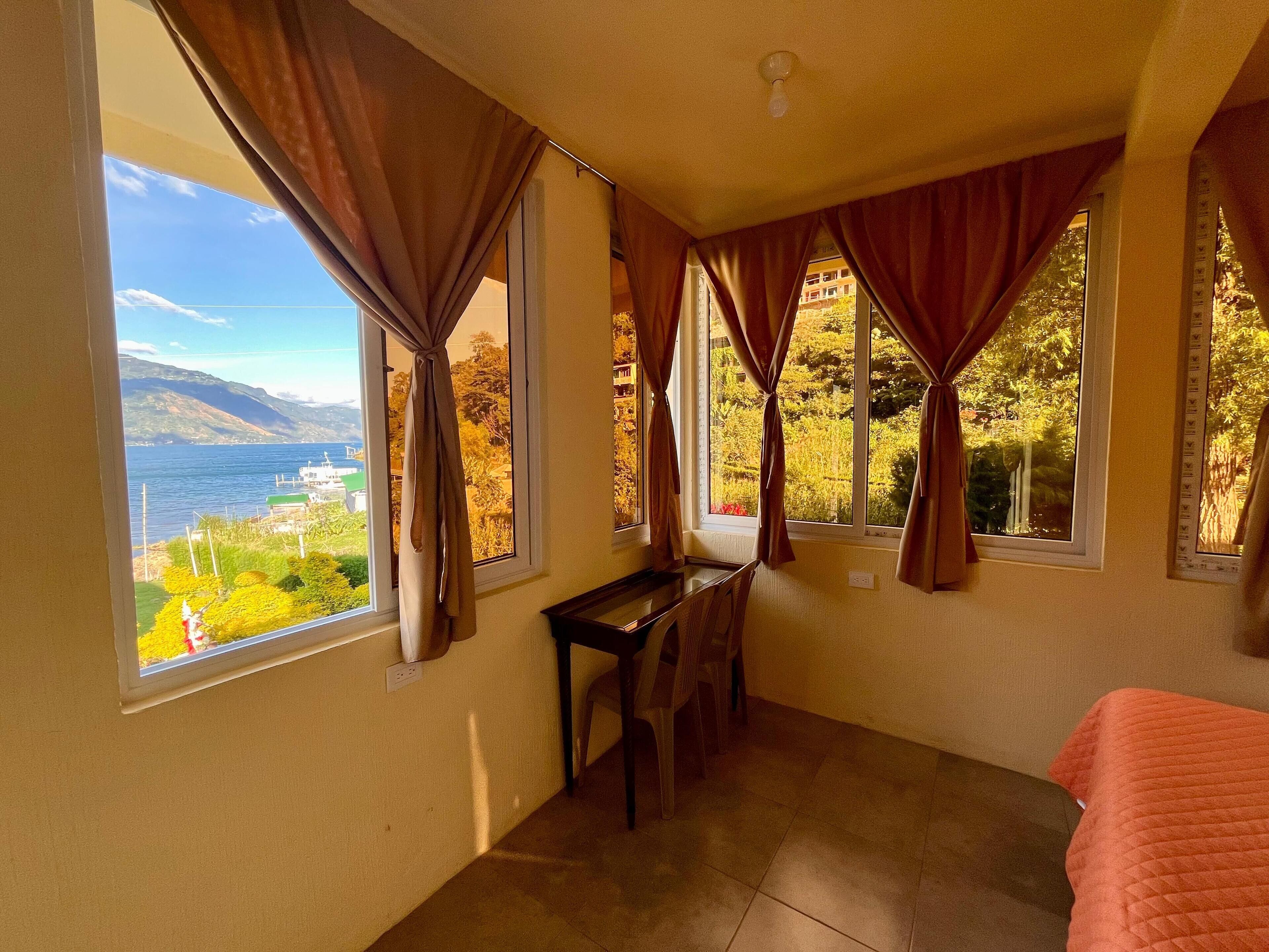 Une chambre avec vue sur un lac et des montagnes, un bureau et un lit.