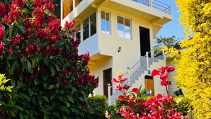 A modern two-story building with a balcony, surrounded by lush greenery and vibrant flowers. - Hotel Casa Ki'iil San Juan La Laguna  (San Juan La Laguna)