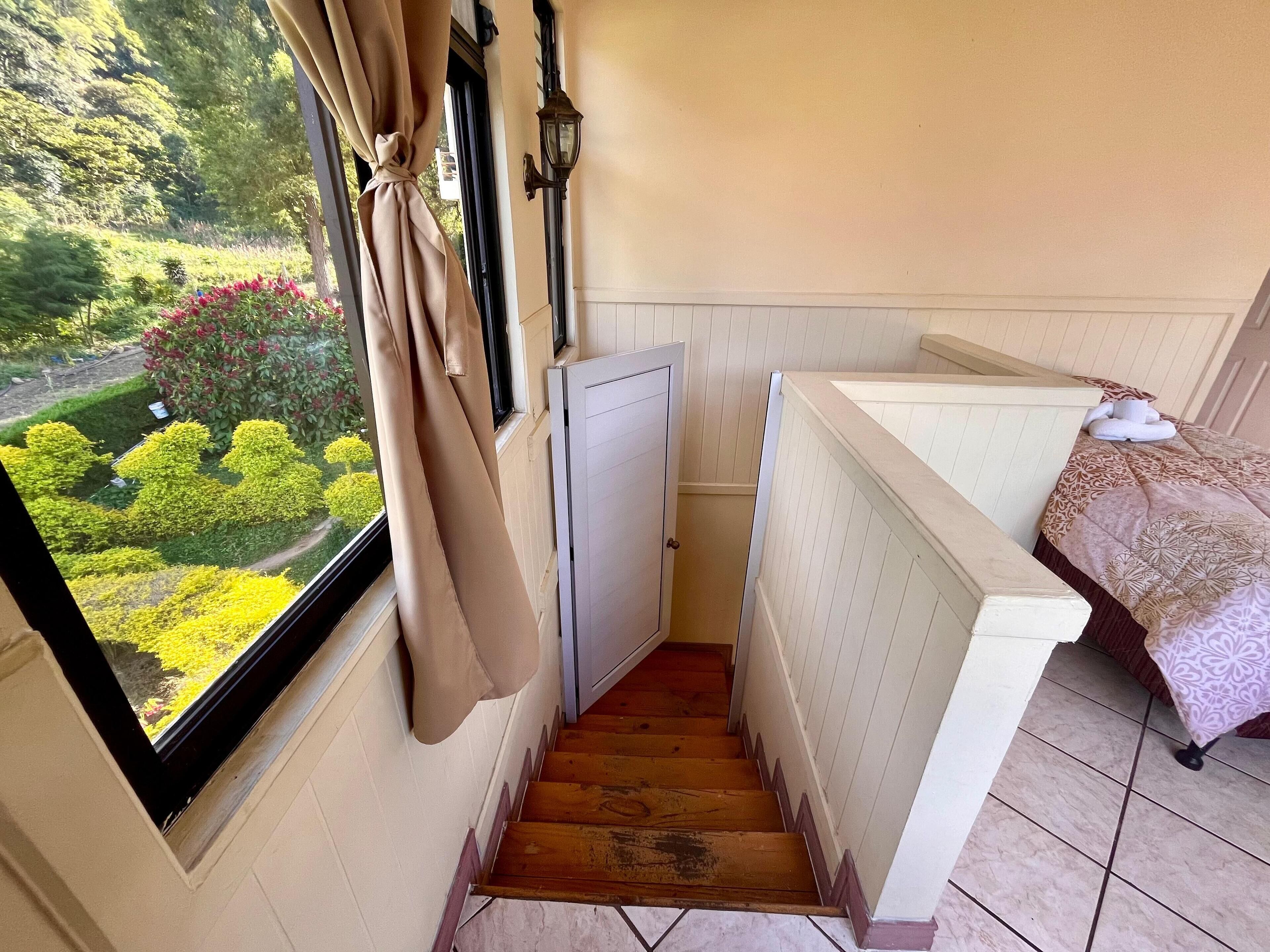 Een smalle trap die leidt naar een slaapkamer met uitzicht op een tuin.